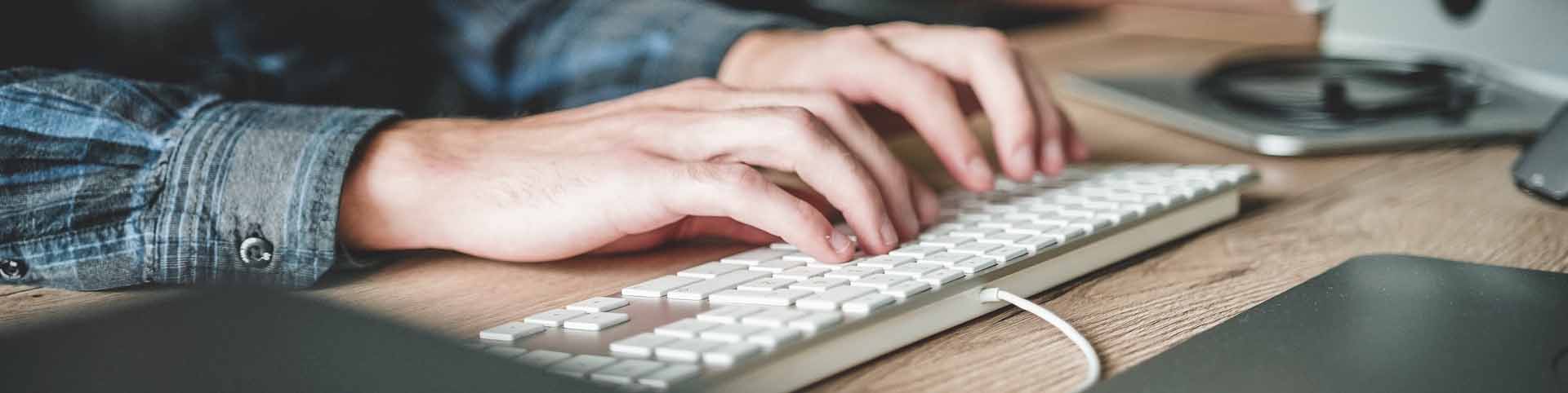 bg-person-hands-typing-on-desktop-keyboard